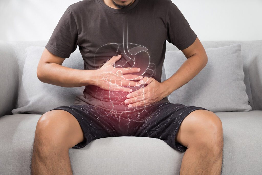 A man sitting on a couch, holding his stomach.