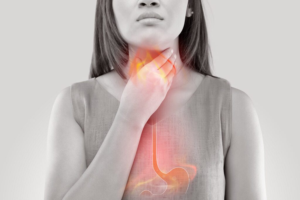 A woman holding her throat, indicating acid reflux.
