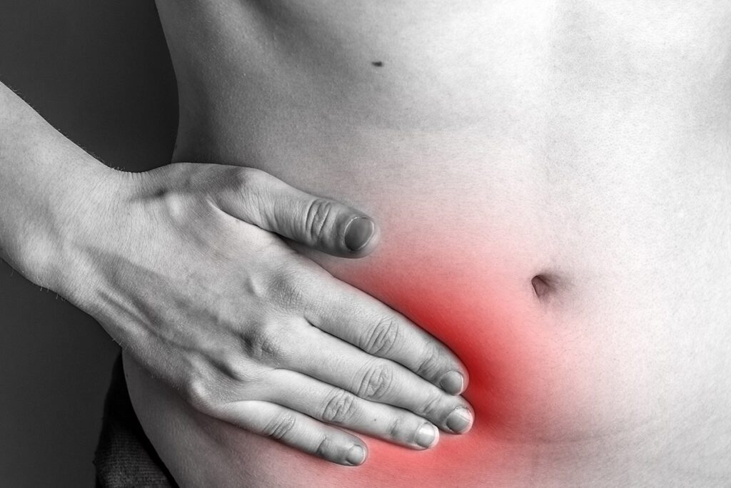Hand covering a section of the exposed stomach where a hernial bulge might appear.