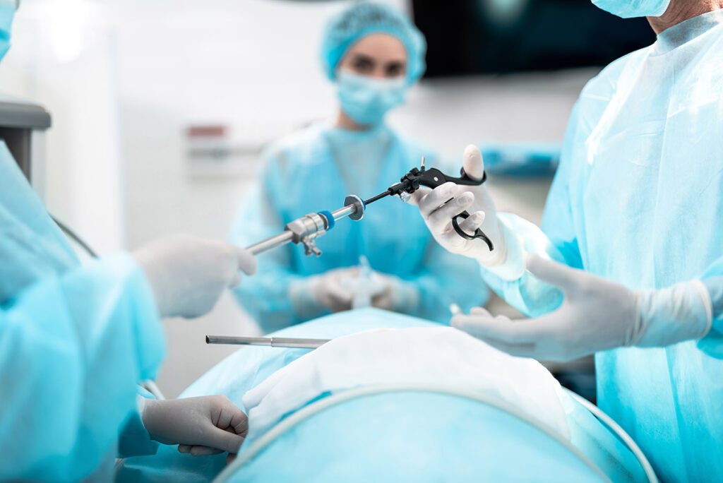 Nurse handing tools for a laparoscopic procedure to a doctor.
